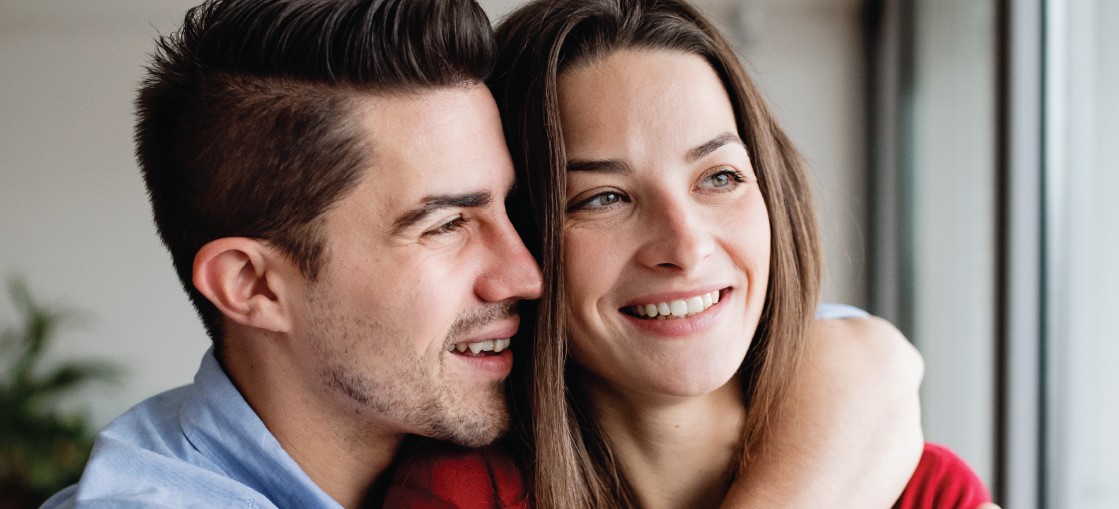 Ein Paar umarmt sich und lächelt. Sie sind glücklich und entspannt.