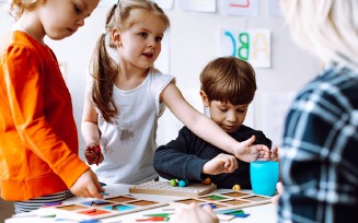 Kinder spielen am Tisch. Verschiedene Spielzeuge und eine Frau.