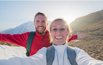 Paar macht Selfie in den Bergen. Lächeln in die Kamera.