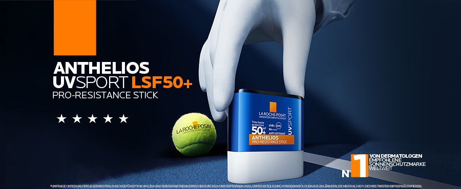 Hand hält La Roche Posay Anthelios UVsport Sonnenschutzstift LSF 50+ neben einem Tennisball.