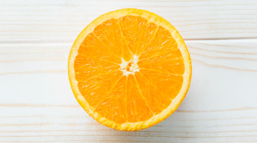 Nahaufnahme einer halbierten Orange auf hellem Holz. Sichtbare Textur und Farbe.