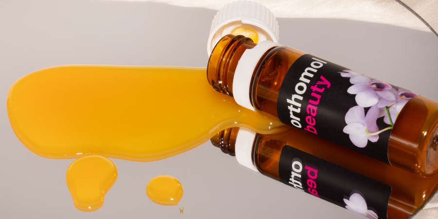 Ampulle und Packung Orthomol Beauty. Produkt auf rosa Untergrund.